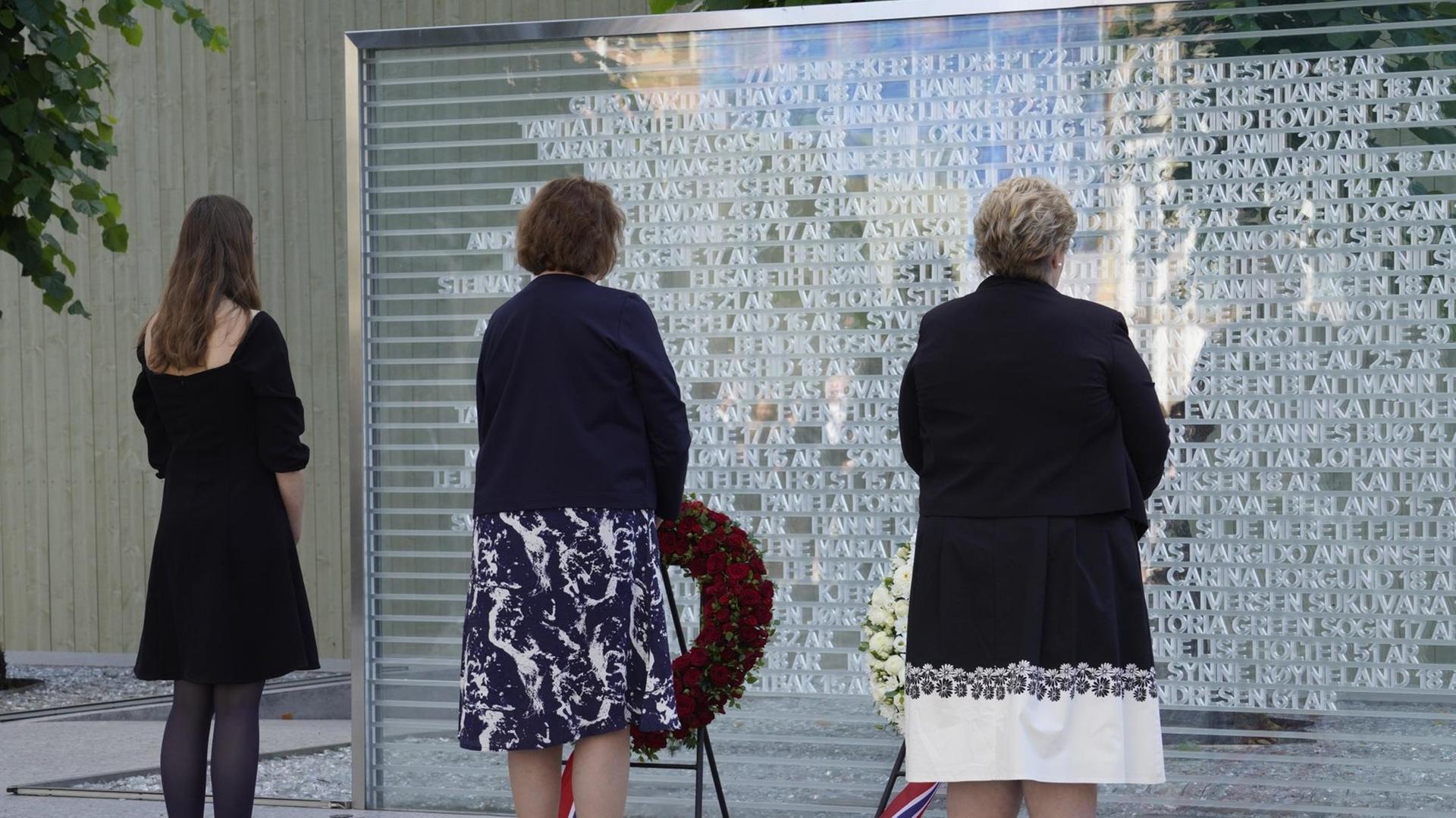 Erinnerung an das Massaker von Utoya 2011, drei Personen stehen vor einer Gedenktafel