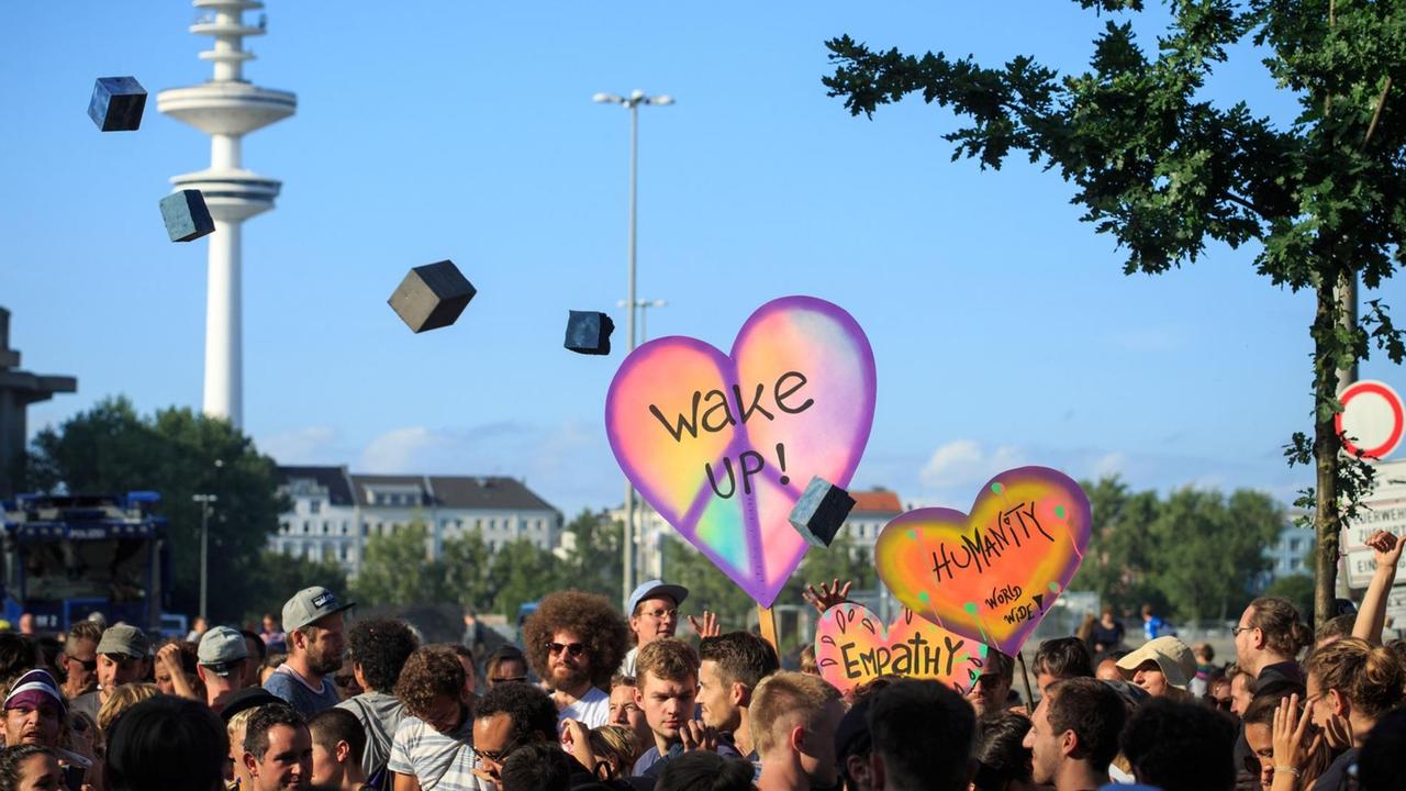 Menschen tanzen vor dem Millerntorstadion in Hamburg unter fliegenden Schaumstoffziegelsteinen.