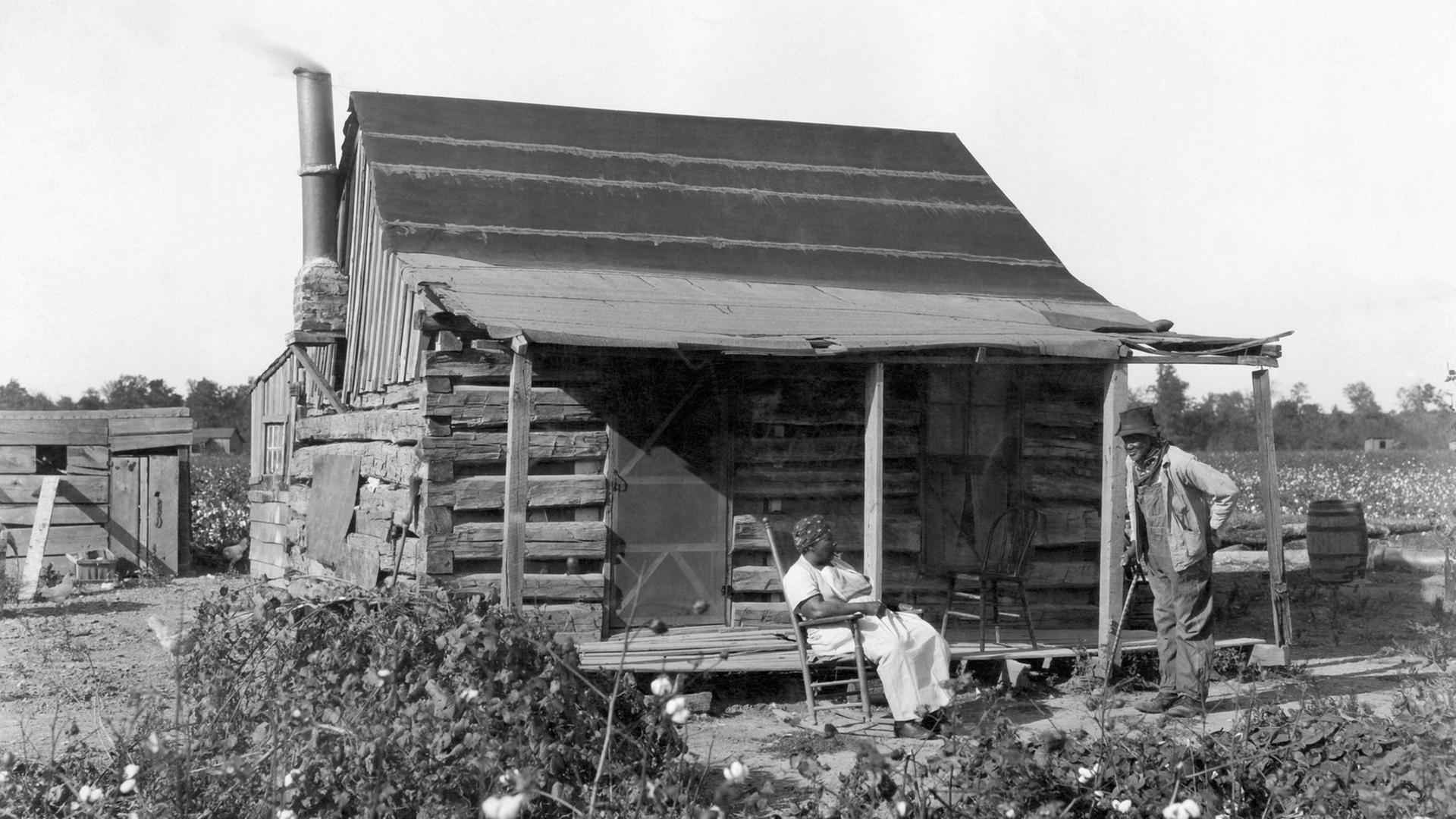 Sklaven im Jahre 1895 vor ihrer Hütte auf einem Baumwollfeld.