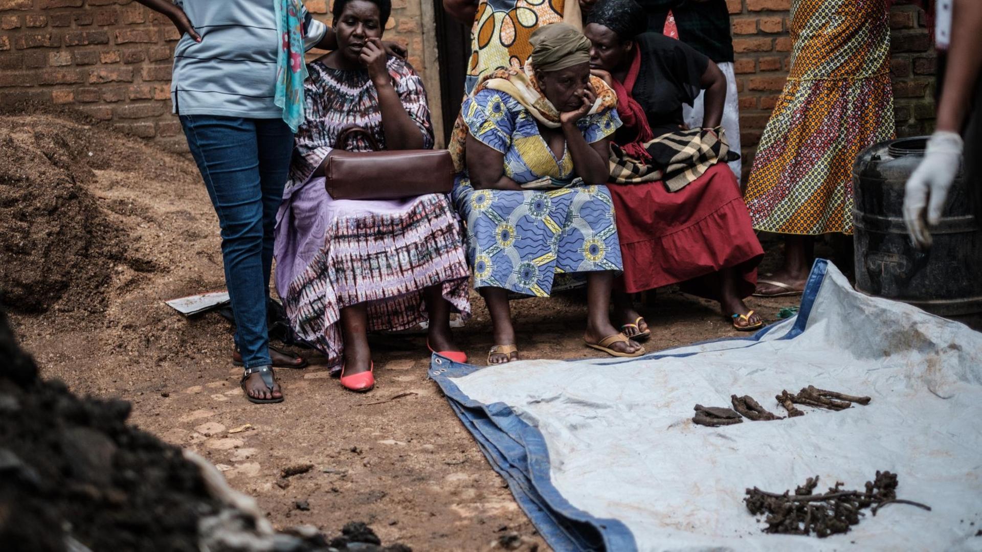 Ausgegrabene Knochen in einem Massengrab in Kabuga, Ruanda. Im Hintergrund sind mehrere Menschen zu erkennen. Ausgegrabene Knochen in einem Massengrab in Kabuga, Ruanda. Im Hintergrund sind mehrere Menschen zu erkennen.