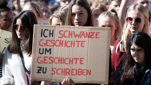 Eine Schülerin hält im Rahmen einer FridaysforFuture-Demonstration ein Plakat hoch mit der Aufschrift: Ich schwänze Geschichte, um Geschichte zu schreiben. 