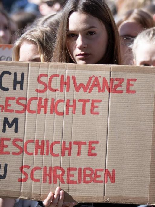 Eine Schülerin hält im Rahmen einer FridaysforFuture-Demonstration ein Plakat hoch mit der Aufschrift: Ich schwänze Geschichte, um Geschichte zu schreiben. 