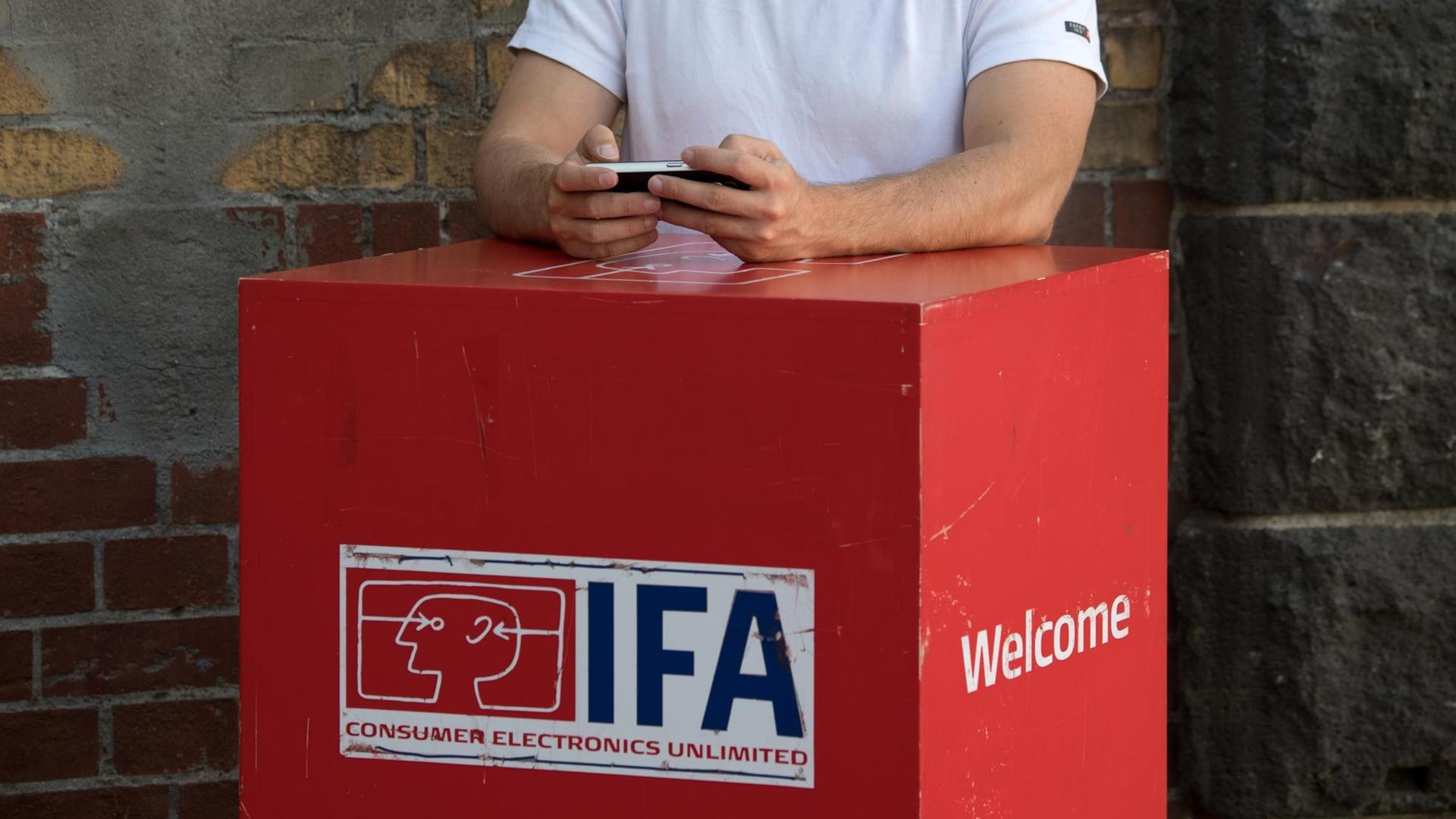 23.08.2018, Berlin: Vor der IFA-Auftakt-Pressekonferenz in Berlin hantiert ein Mann mit seinem Smartphone. Die Unterhaltungselektronik-Messe findet vom 31. August bis 5. September auf dem Berliner Messegelände statt. Foto: Ralf Hirschberger/dpa | Verwendung weltweit