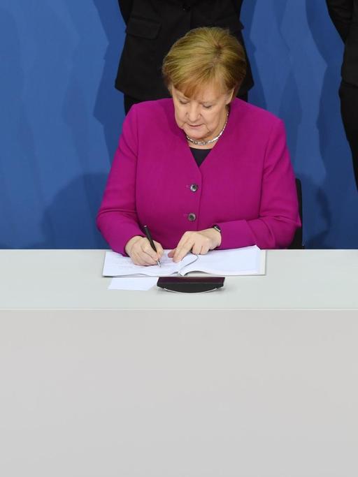 Bundeskanzlerin Angela Merkel (CDU), der CSU-Vorsitzende Horst Seehofer (r) und der kommissarische SPD-Vorsitzende Olaf Scholz unterzeichnen im Paul-Löbe-Haus den Koalitionsvertrag.