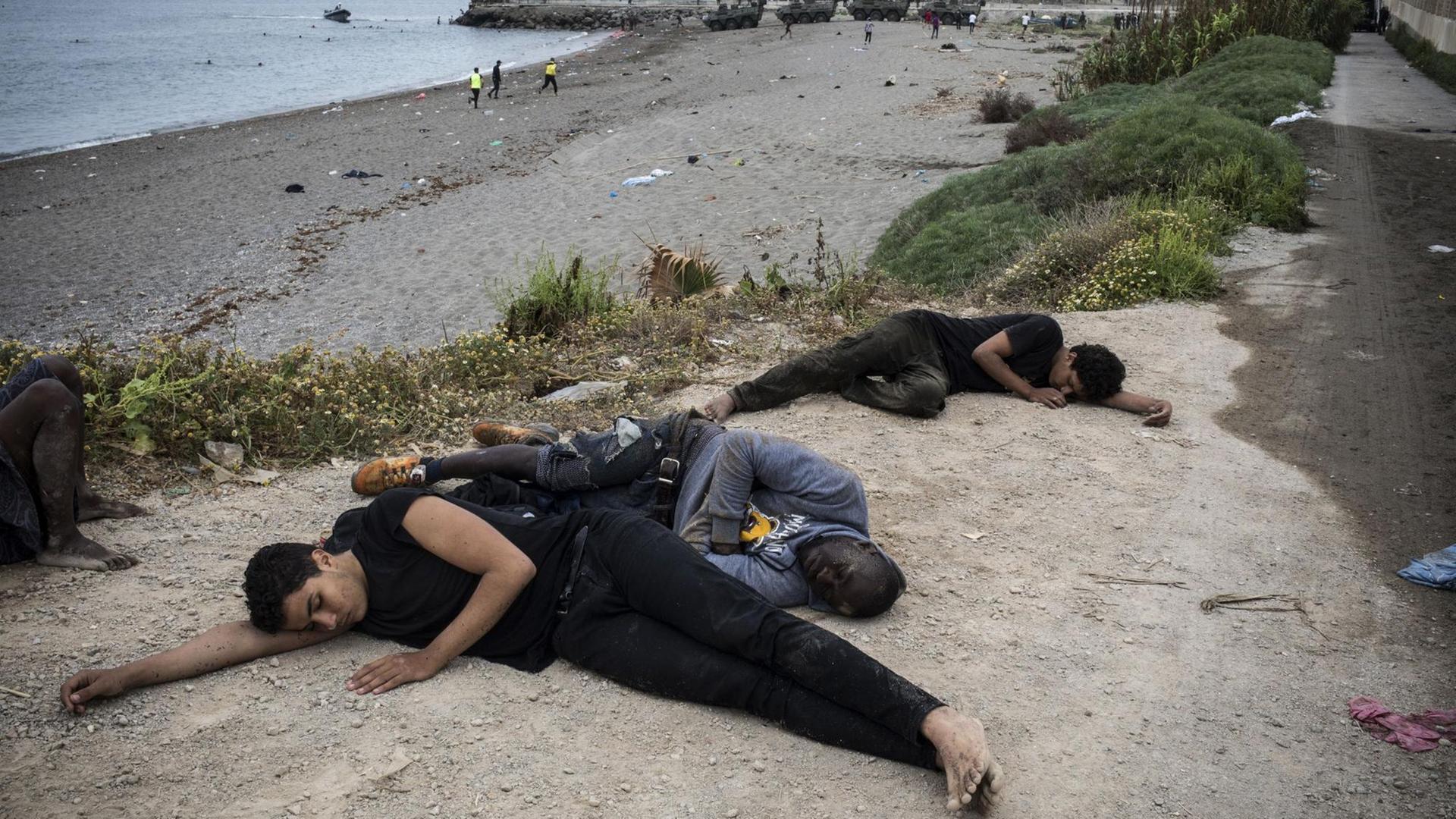 Menschen liegen erschöpft am Strand