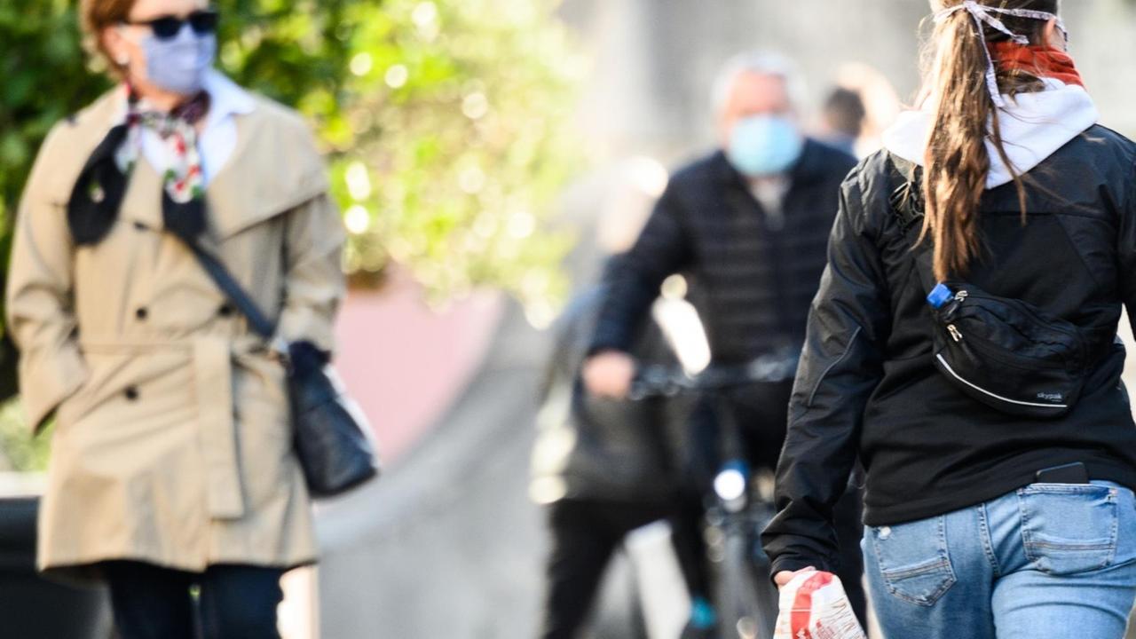 Menschen gehen durch die Fußgängerzone in Darmstadt, wo Maskenpflicht gilt