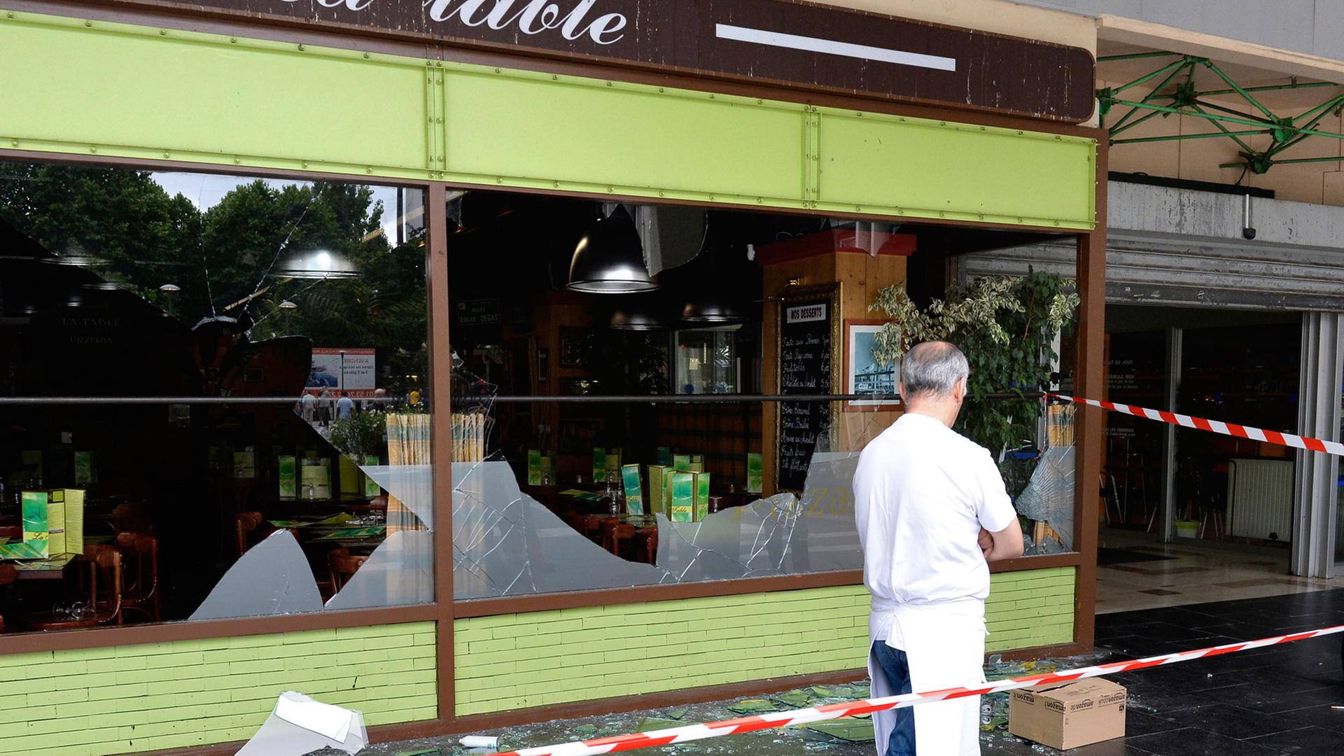 Ein Mann läuft hinter der Absperrung vor den Fenstern eines Restaurants im Pariser Bezirk Sarcelles, die bei Demonstrationen zerstört wurden.