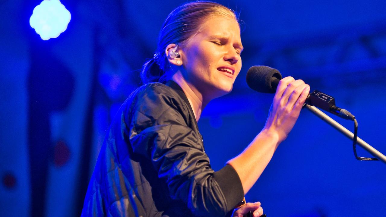 Die Musikerin Maarja Nuut hält ein Mikrofon in der Hand,  in das sie singt