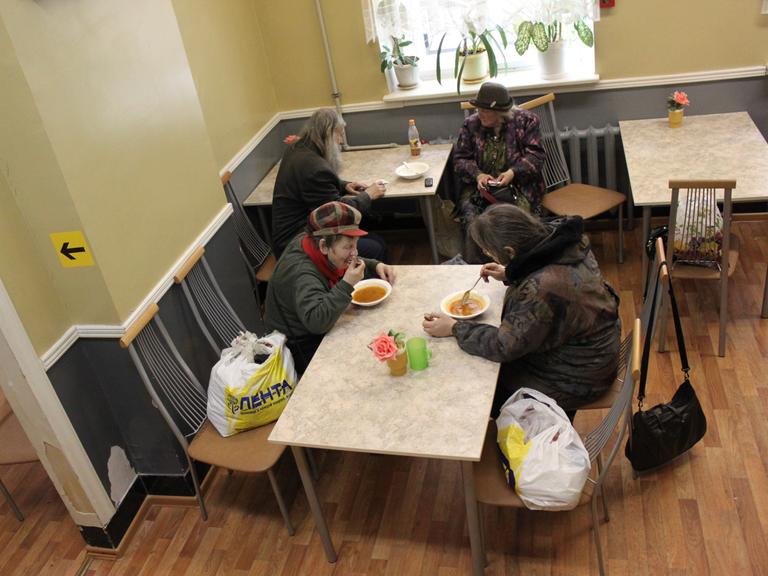 Blick von oben in einen Speisesaal, an zwei Tischen sitzen jeweils zwei ältere Frauen und essen Suppe und unterhalten sich.