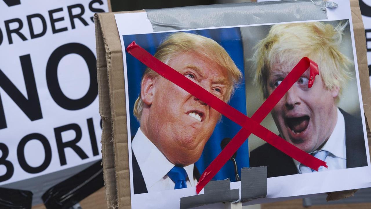 Ein Plakat mit Kariakturen von Donald Trump und Boris Johnson, die durchgestrichen sind. Andere Plakate zeigen die Aufschrit "No Borders".