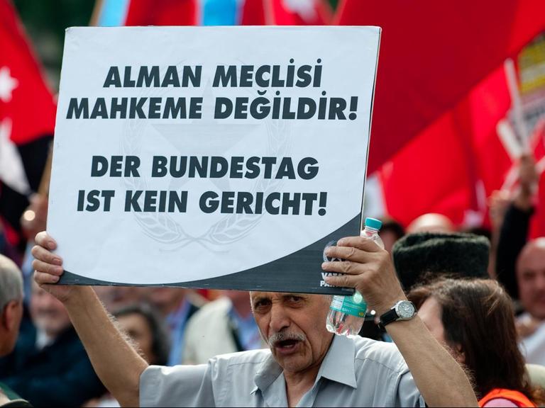 Teilnehmer der Demonstration halten ein Schild hoch mit dem Slogan "Der Bundestag ist kein Gericht".