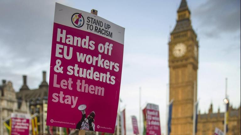 Eine Frau demonstriert am 13. Mäerz 2017 vor dem Parlament in London dafür, dass Studenten und Arbeiter aus der EU auch nach dem Brexit in Großbritannien bleiben dürfen. Auf ihrem Schild steht: "Hands off EU-workers and students - Let them stay!"