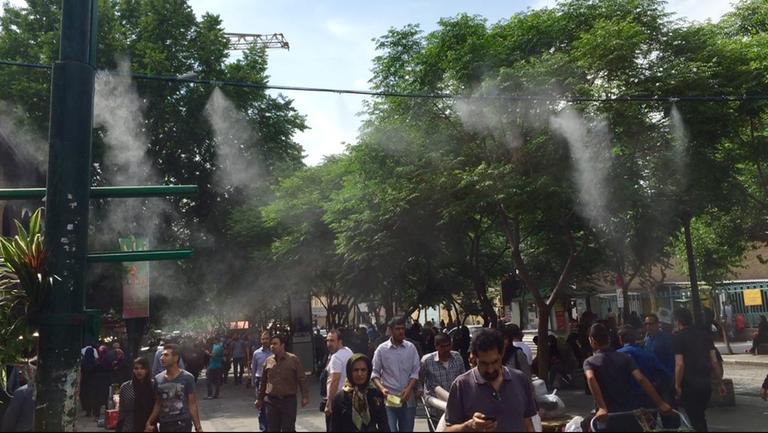 Vor dem Großen Basar von Teheran versprühen Schläuche kühlenden Wasserdampf.