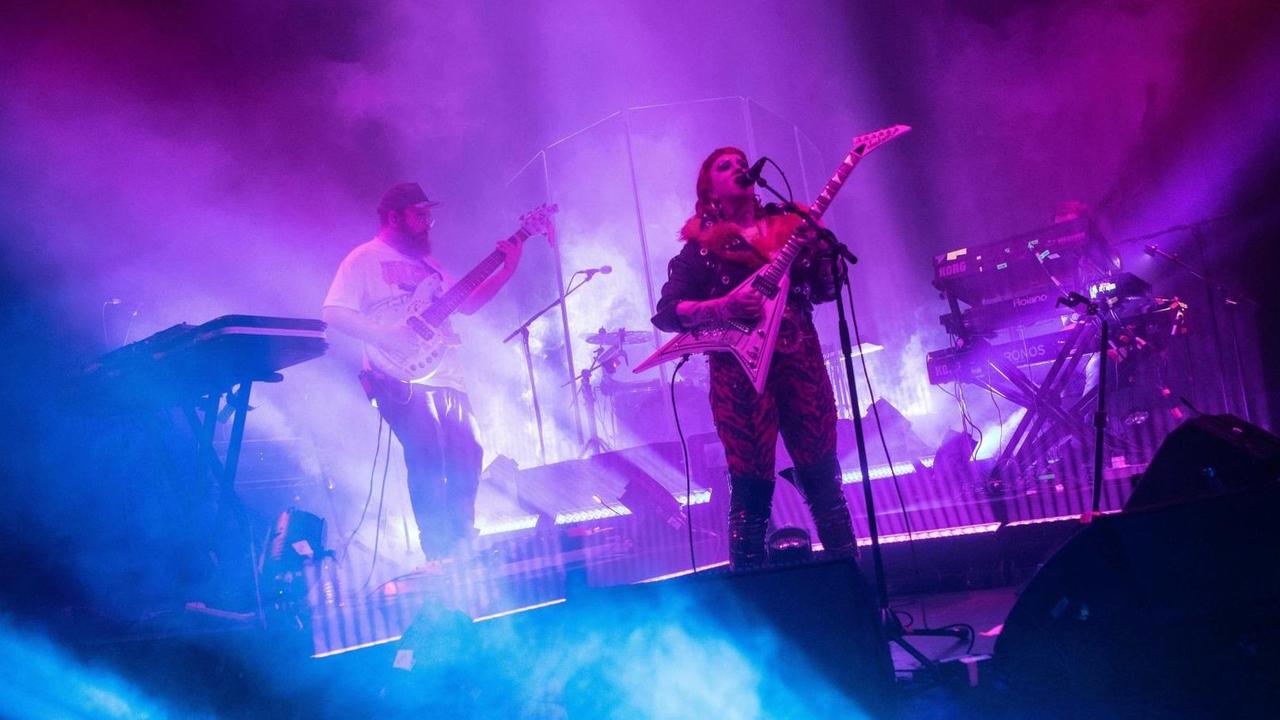 Die australische Band Hiatus Kaiyote im November 2019 live in London: In blauem und violetten scheinwerferlicht sind ein Mann und eine Frau jeweils mit einer Gitarre auf einer Bühne zu sehen.