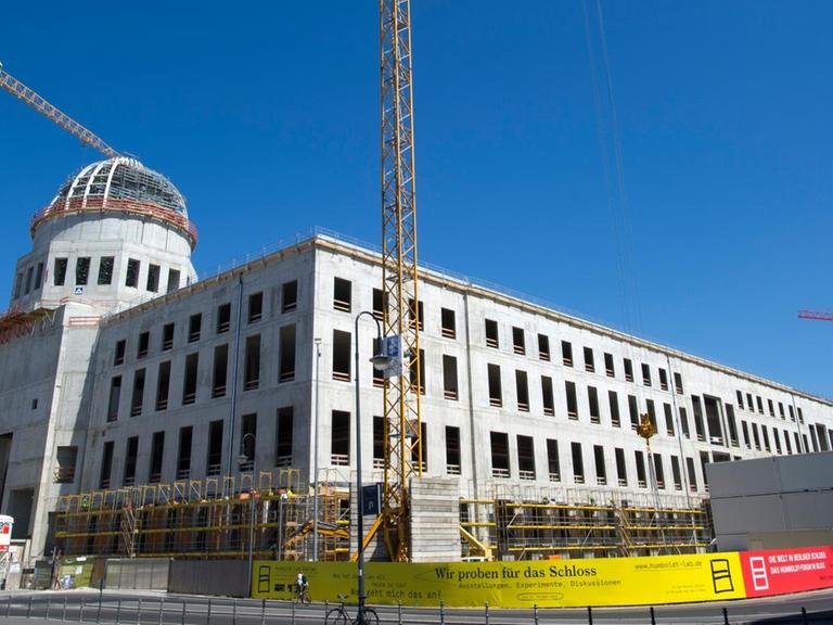 Baukräne ragen an der Baustelle des neuen Berliner Stadtschlosses in den blauen Himmel.