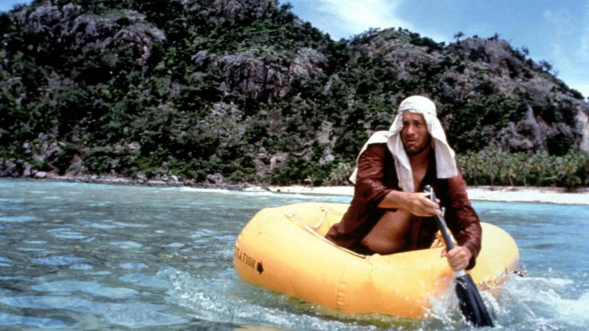Filmstill aus dem Kinofilm Cast Away mit Tom Hanks. Das Bild zeigt einen ausgemärgelten Mann mit Turban in einem Schlauboot vor einer einsamen Insel.