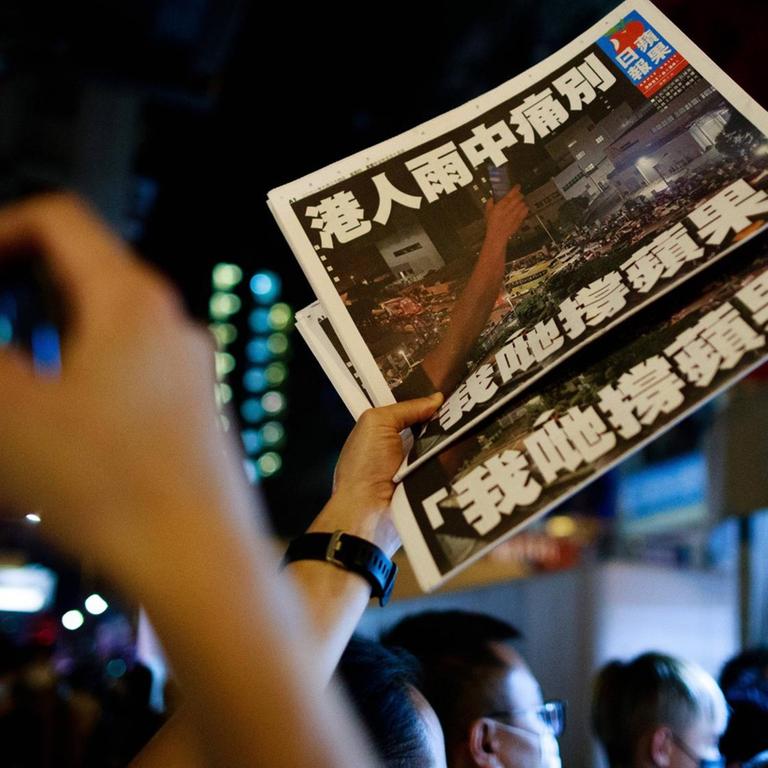 Ein Mann hält zwei exemplare der letzten Ausgabe der Hongkonger Tageszeitung "Apple Daily" in die Höhe.