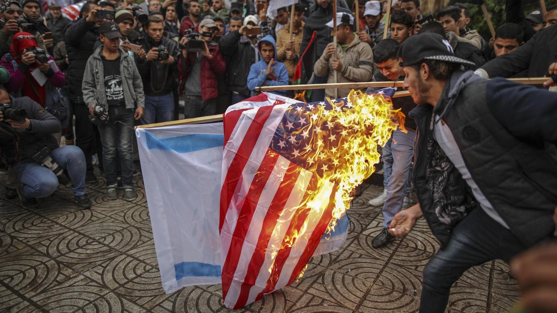 Palästinenser verbrennen am 06.12.2017 in Gaza (Palästinensische Autonomiegebiete) während eines Protests gegen US-Präsident Trumps Vorhaben, Jerusalem als Hauptstadt Israels anzuerkennen, die amerikanische und israelische Flagge. (zu dpa «Trump legt mit Jerusalem die Lunte an das Pulverfass Nahost» vom 06.12.2017)