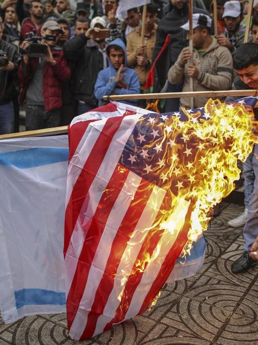 Palästinenser verbrennen am 06.12.2017 in Gaza (Palästinensische Autonomiegebiete) während eines Protests gegen US-Präsident Trumps Vorhaben, Jerusalem als Hauptstadt Israels anzuerkennen, die amerikanische und israelische Flagge. (zu dpa «Trump legt mit Jerusalem die Lunte an das Pulverfass Nahost» vom 06.12.2017)