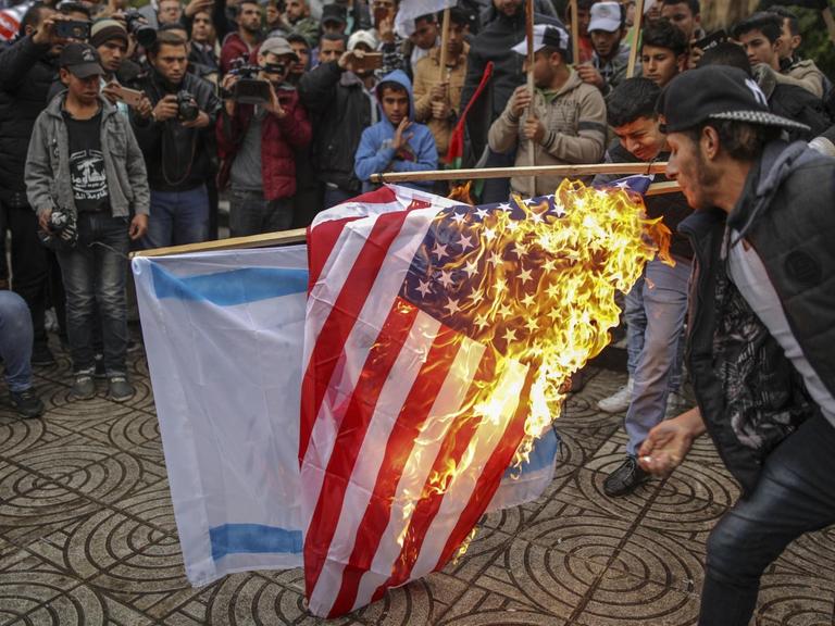 Palästinenser verbrennen am 06.12.2017 in Gaza (Palästinensische Autonomiegebiete) während eines Protests gegen US-Präsident Trumps Vorhaben, Jerusalem als Hauptstadt Israels anzuerkennen, die amerikanische und israelische Flagge. (zu dpa «Trump legt mit Jerusalem die Lunte an das Pulverfass Nahost» vom 06.12.2017)