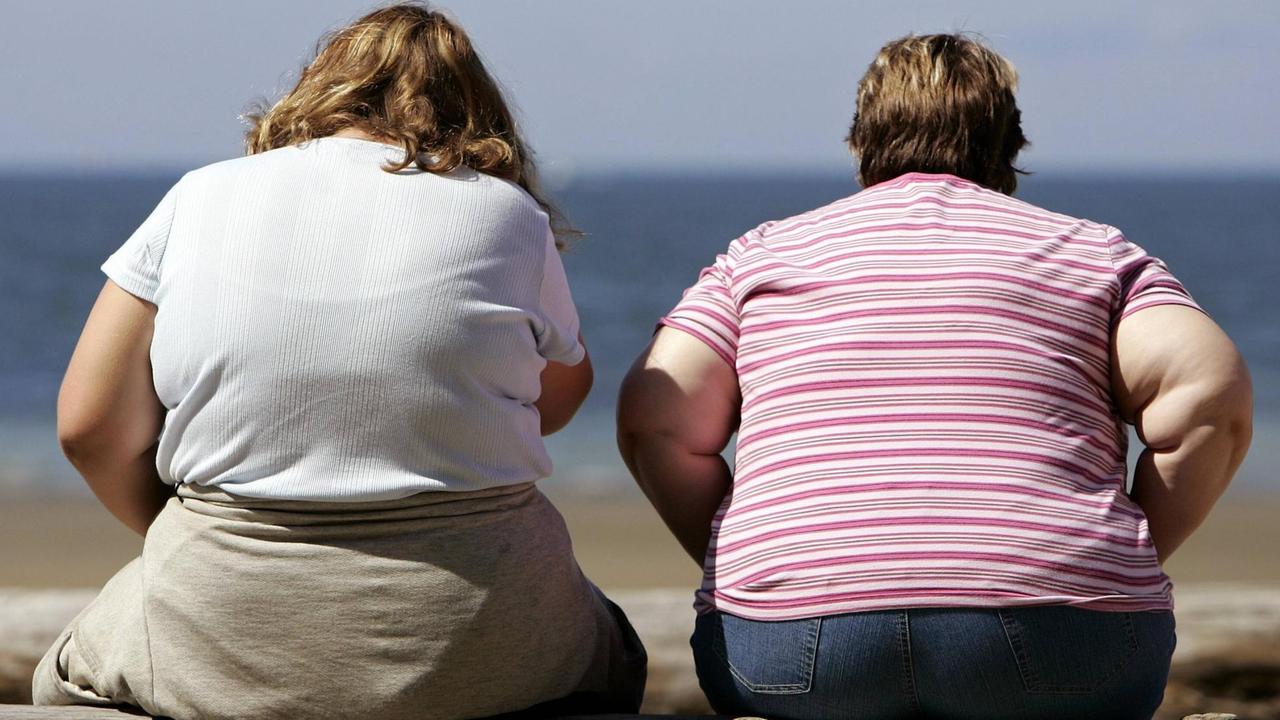 Zwei beleibte Frauen sitzen am Strand von British Columbia.