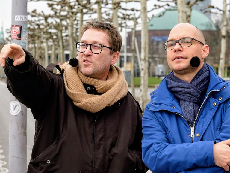 Der Schriftsteller Jan Weiler zeigt Richtung Oberkassel: In diesem Stadtteil von Düsseldorf hat er mal gewohnt, rechts im Bild Moderator Korbinian Frenzel
