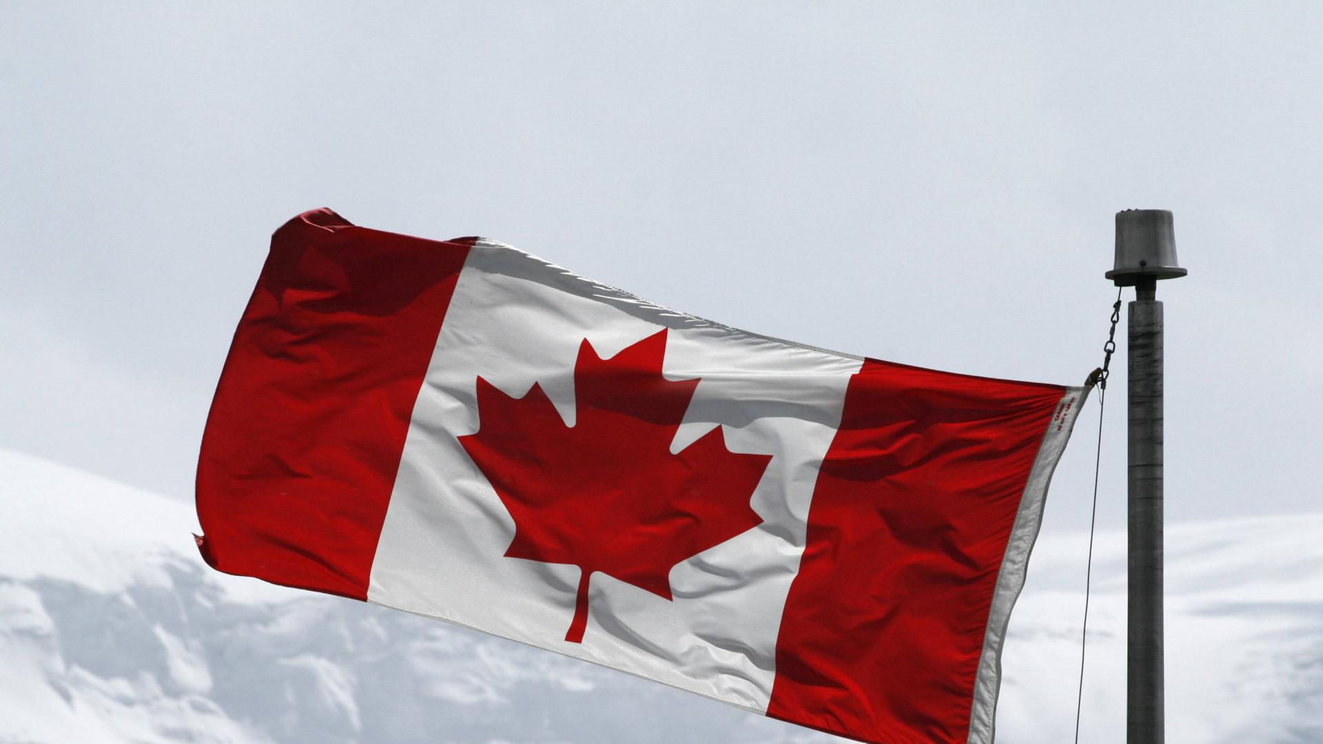 Die kanadische Flagge in einem schneebedeckten Gebirge.