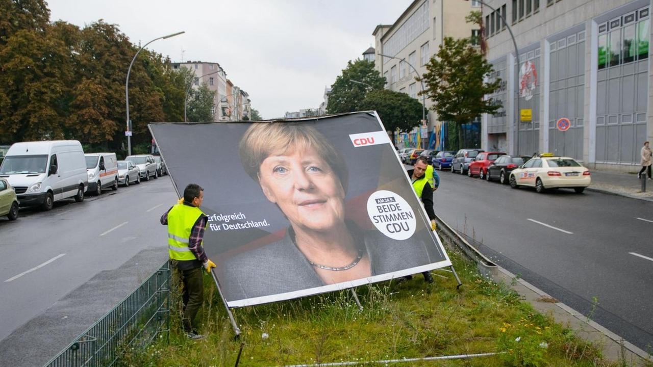 Arbeiter montieren am 25.09.2017 auf einem Grünstreifen im Stadtteil Wedding in Berlin ein Großplakat der CDU ab.