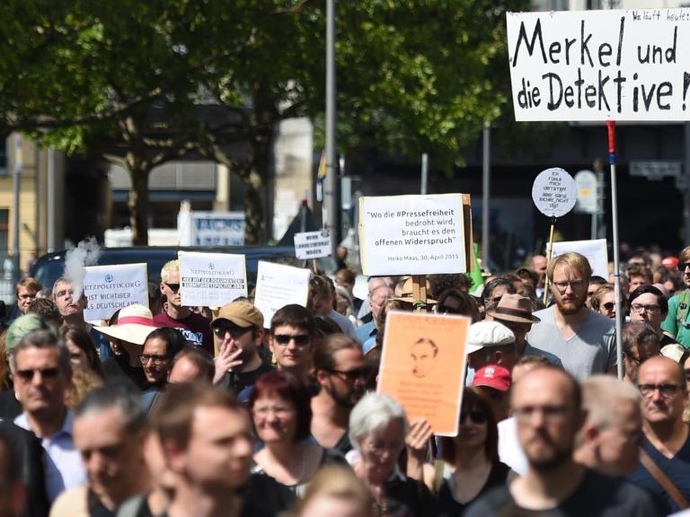 Teilnehmer einer Demonstration von Unterstützern von Netzpolitik.org halten ein Schild hoch, auf dem "Merkel und die Detektive!" steht
