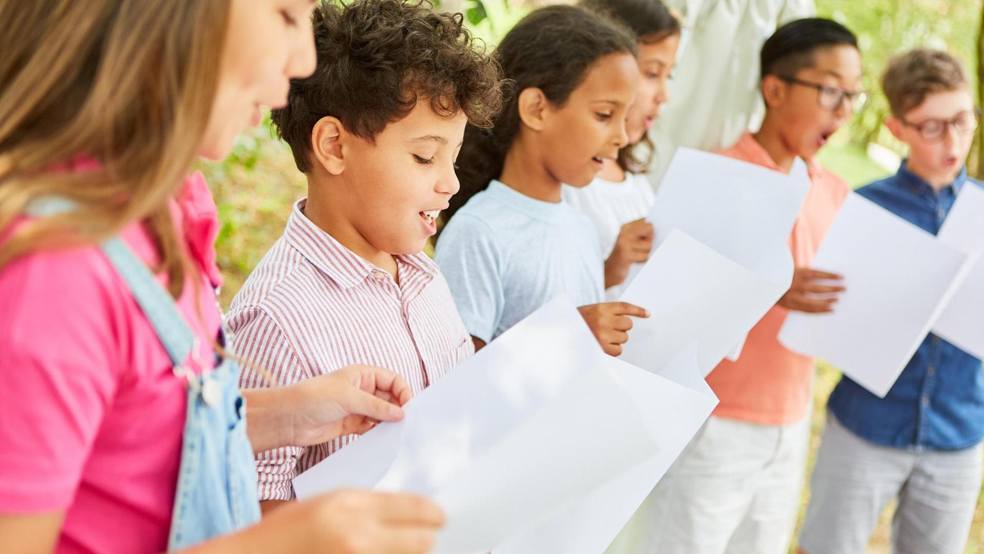Kinder halten Notenblätter und singen