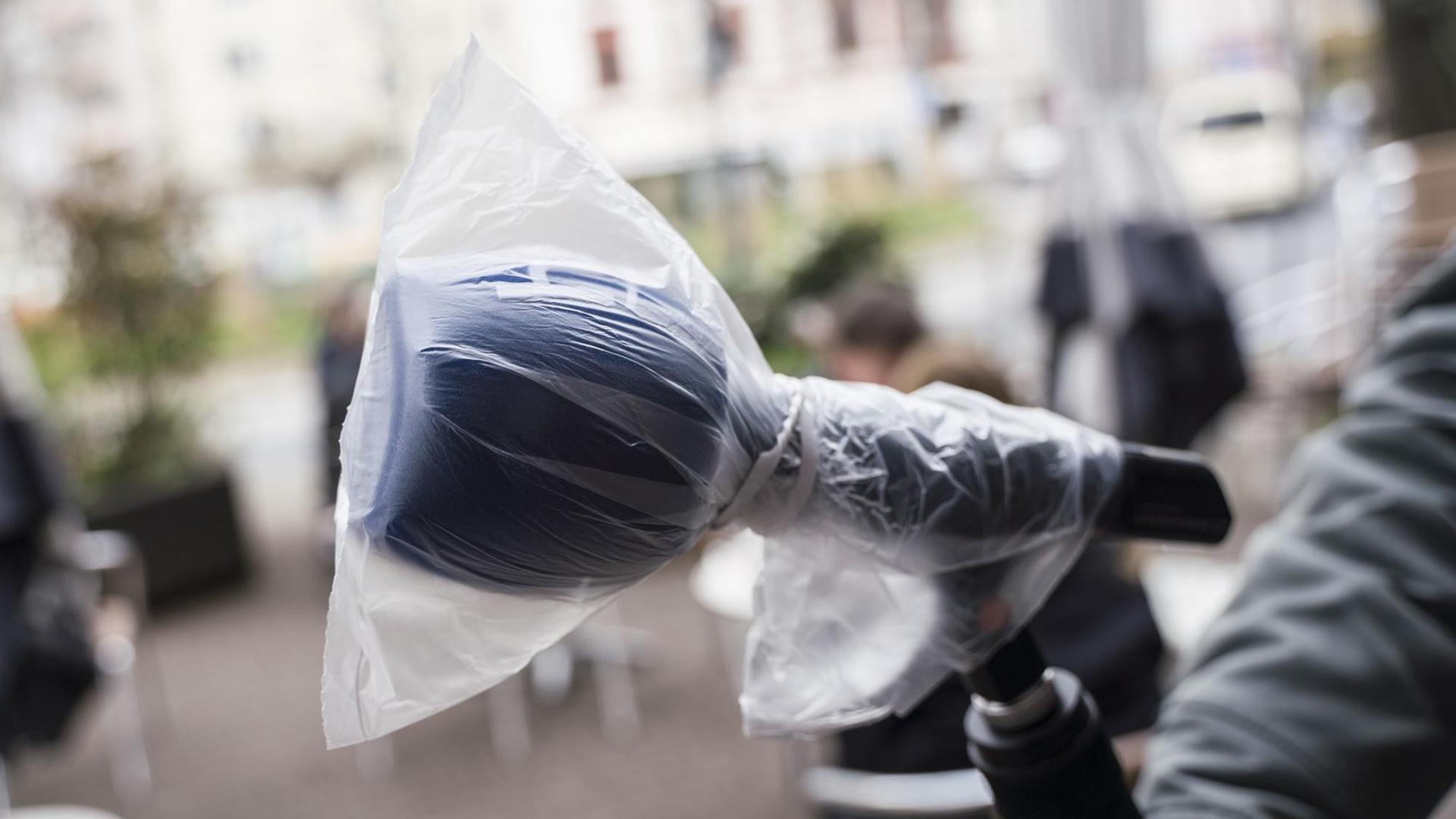 Ein Fernsehjournalist hält bei einer Reportage über die Auswirkungen im öffentlichen Leben in Zeiten der Verbreitung des Coronavirus ein Mikrofon, das mit einer Plastiktüte vor Viren geschützt werden soll. Ein Fernsehjournalist hält bei einer Reportage über die Auswirkungen im öffentlichen Leben in Zeiten der Verbreitung des Coronavirus ein Mikrofon, das mit einer Plastiktüte vor Viren geschützt werden soll.