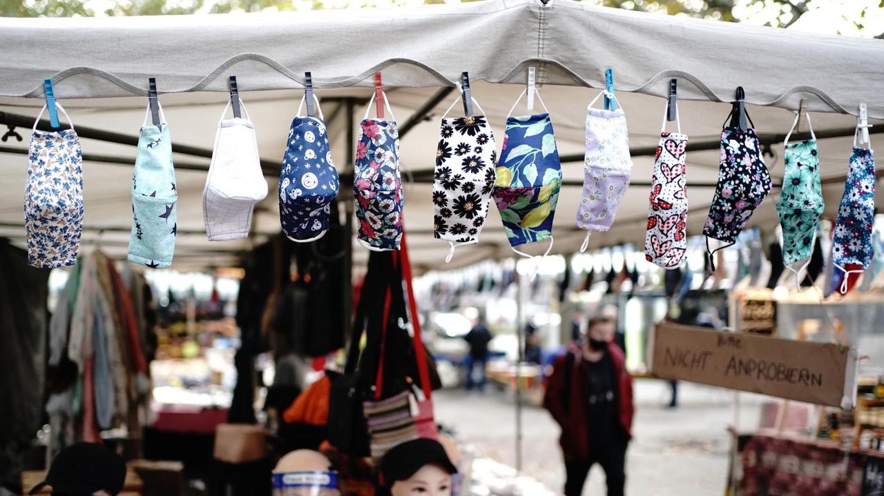 An einem Stand auf einem Wochenmarkt im Berliner Stadtteil Steglitz werden Mund-Nasenbedeckung zum Kauf angeboten.