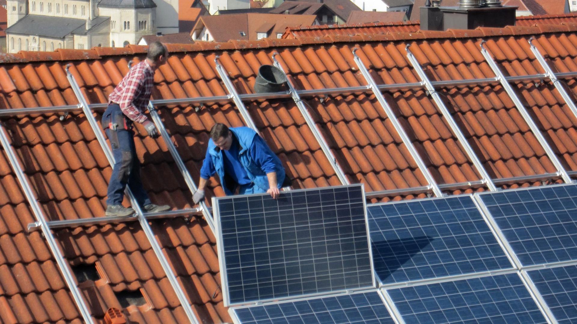 Arbeiter installieren Solarzellen auf einem Dach, aufgenommen am 06.03.2012 in Igersheim.