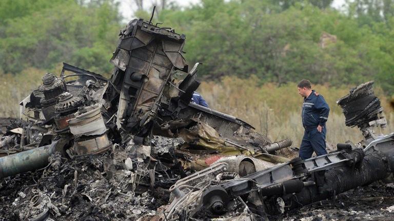 Ein Helfer steht in den vollkommen zerstörten Trümmerteilen der Malaysia-Airlines-Maschine in der Ost-Ukraine