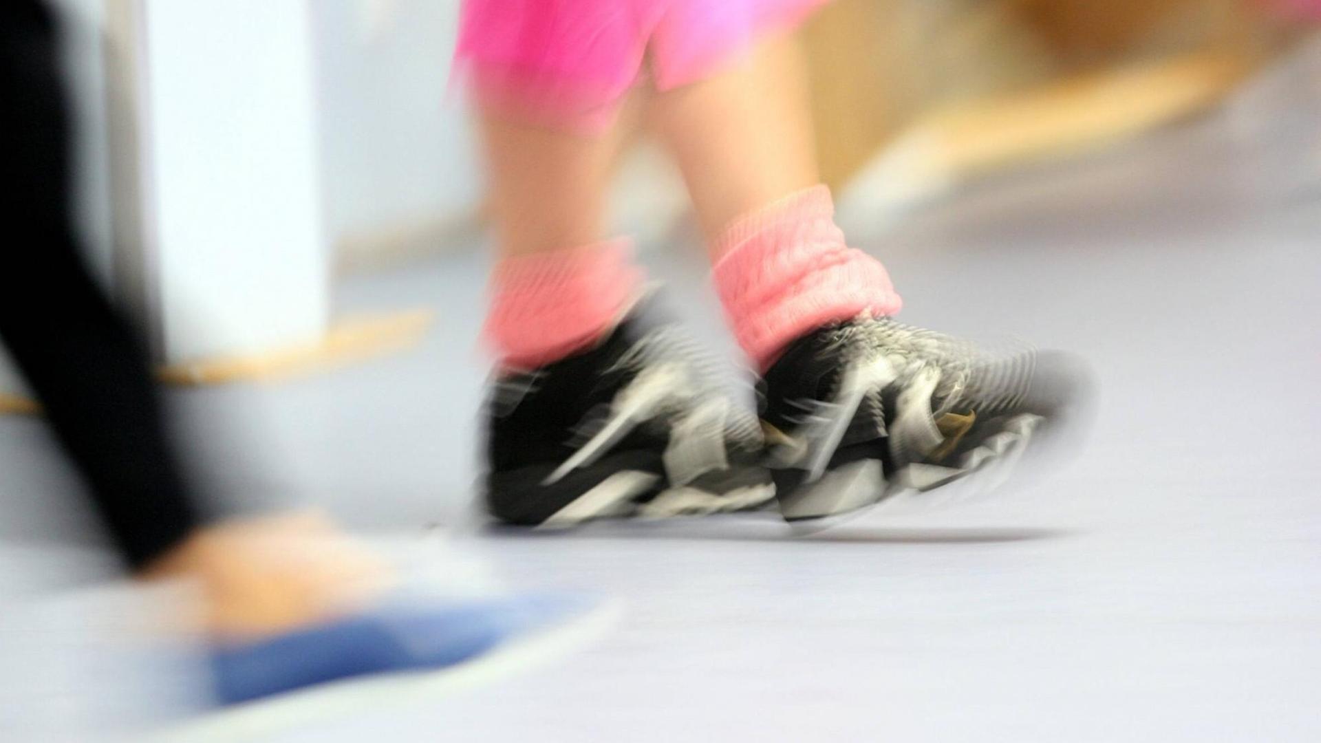 Verschwommenes Bild der Beine von Teilnehmern in einer Sporthalle.