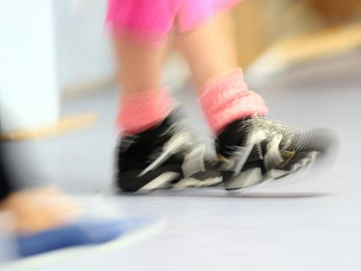 Verschwommenes Bild der Beine von Teilnehmern in einer Sporthalle.