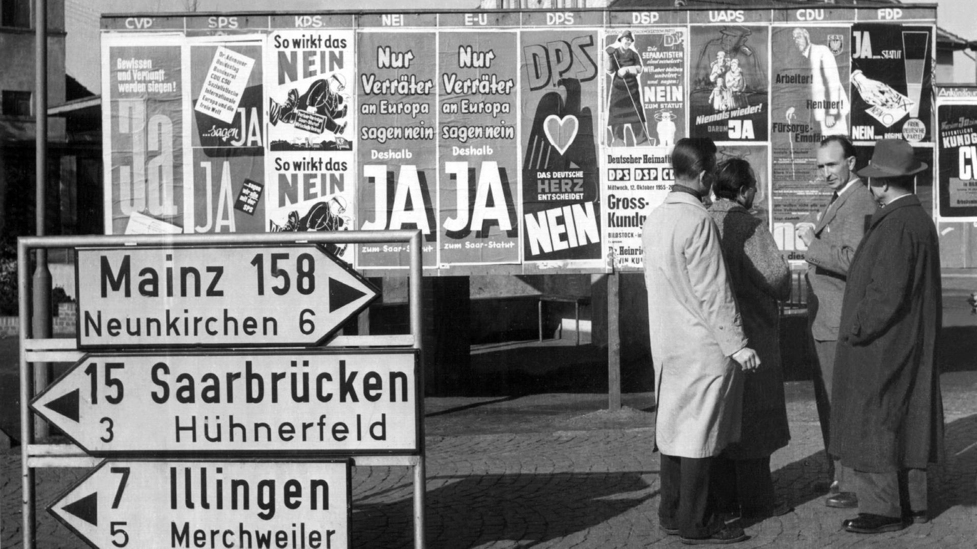 Wahlplakate zum europäischen Saarstatuts in Beckingen, schwarz-weiß, Männer stehen davor und sprechen miteinander