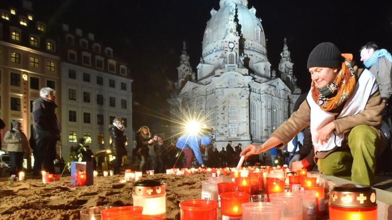 Grablichter und Kerzen brennen während der Gedenkveranstaltung zum 70. Jahrestag der Bombardierung von Dresden. Im Hintergrund die wieder aufgebaute Frauenkirche.