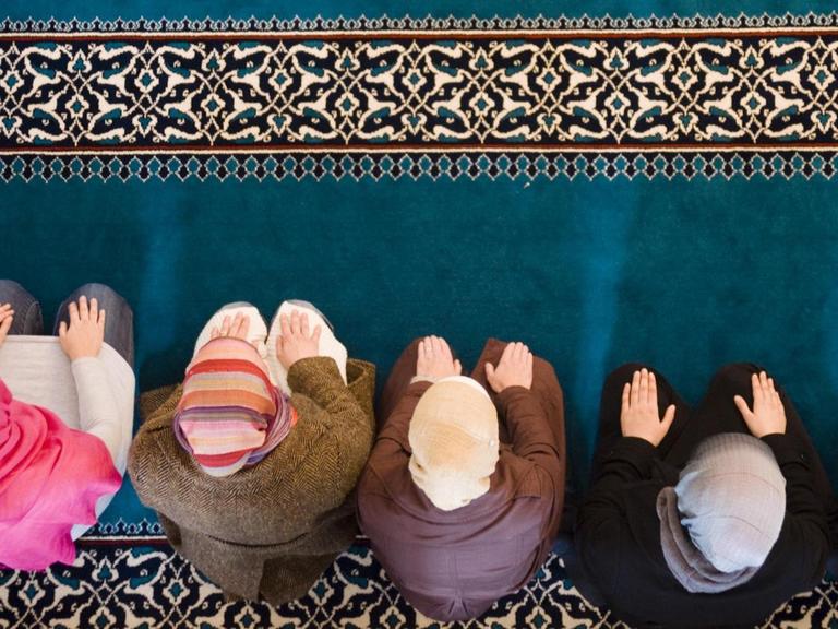Sechs muslimische Frauen beten in der Sehitlik Moschee in Berlin-Neukölln. Das Foto zeigt sie von oben, aus der Vogelperspektive.