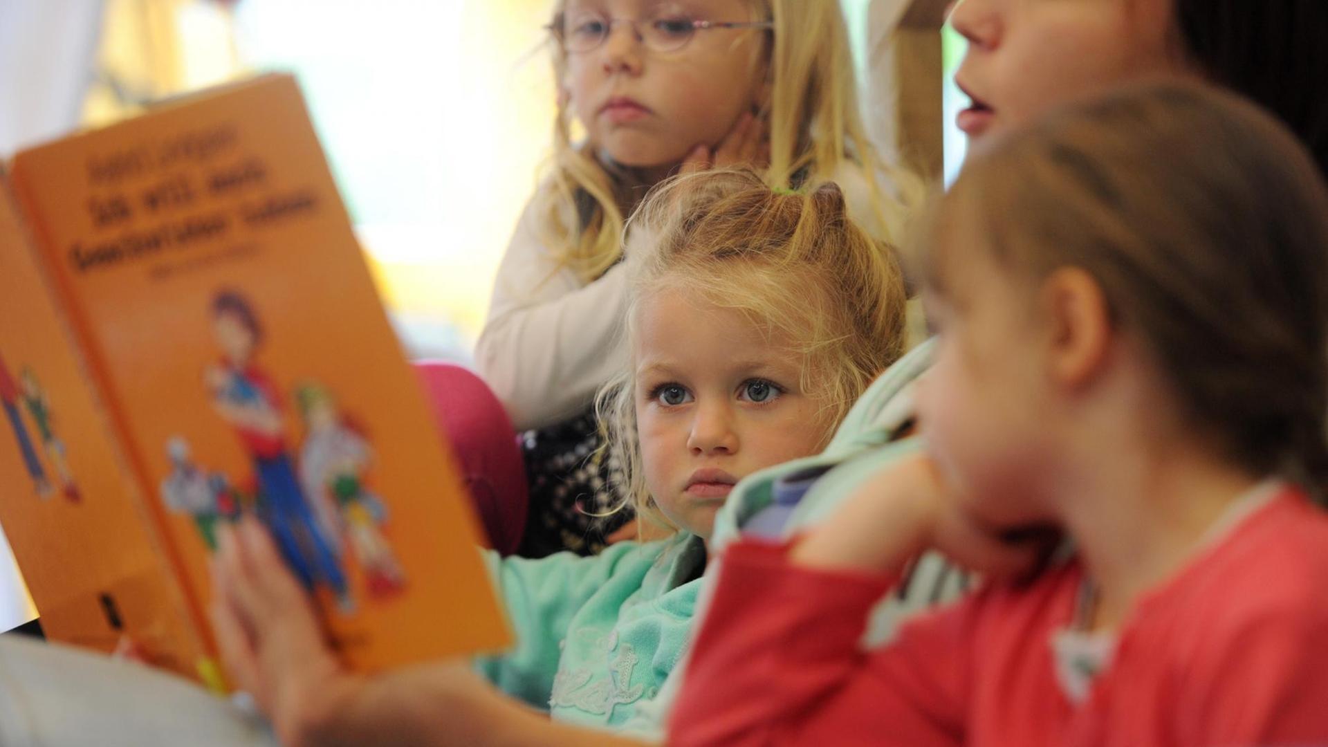 Eine Erzieherin liest Kindern aus einem Buch vor.