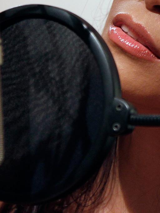 Eine Frau steht mit leicht geöffneten Lippen vor einem Mikrofon.