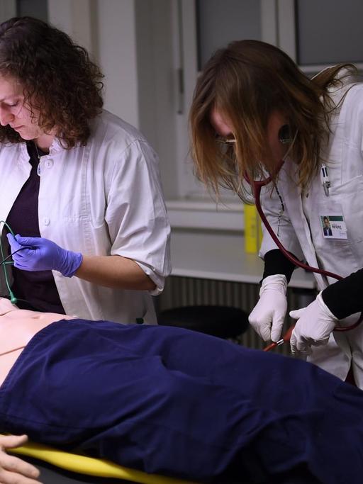 Die Medizinstudenten Marie (l) und Helene führen in der Charité in Berlin bei der Übung "Simulierte Rettungsstelle" eine Notfallbehandlung an einem Dummy durch.