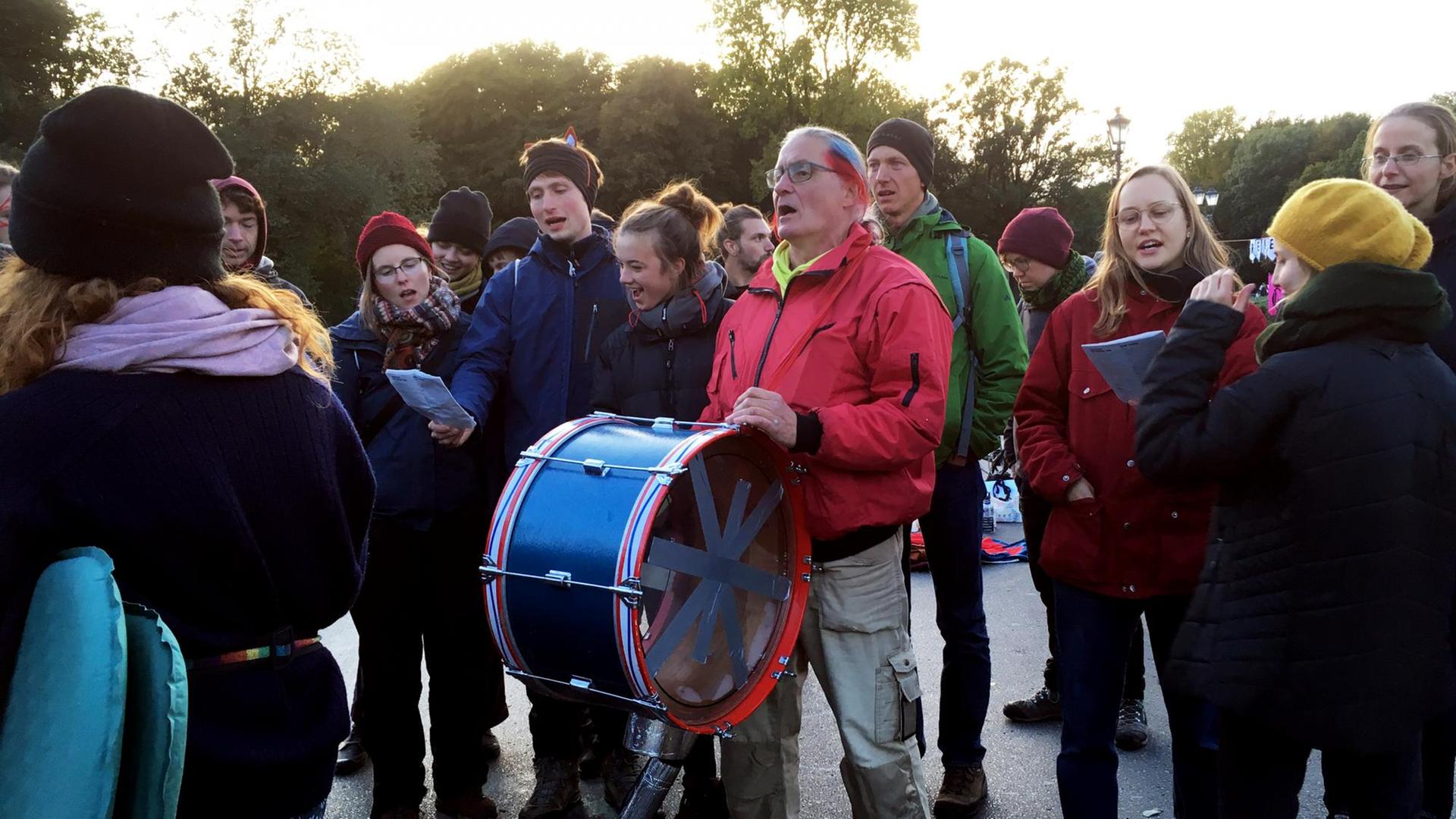 Eine Gruppe Klima-Protestierender steht gemeinsam auf der Straße, mittendrin der Rentner Werner Philippi mit seiner Trommel.