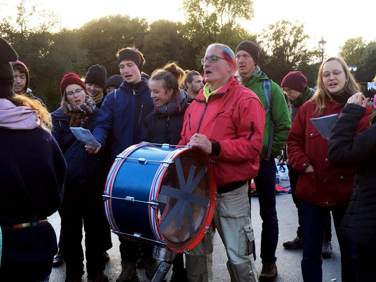 Eine Gruppe Klima-Protestierender steht gemeinsam auf der Straße, mittendrin der Rentner Werner Philippi mit seiner Trommel.