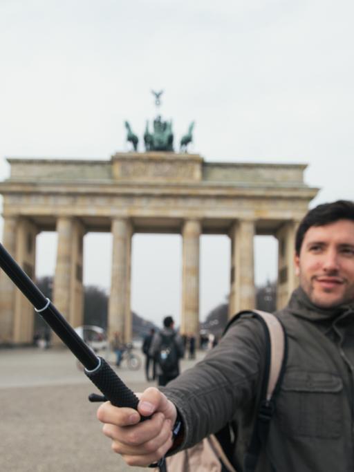 Zwei Touristen machen am Brandenburger Tor in Berlin ein Selbstporträt mit einem "Selfie-Stick"
