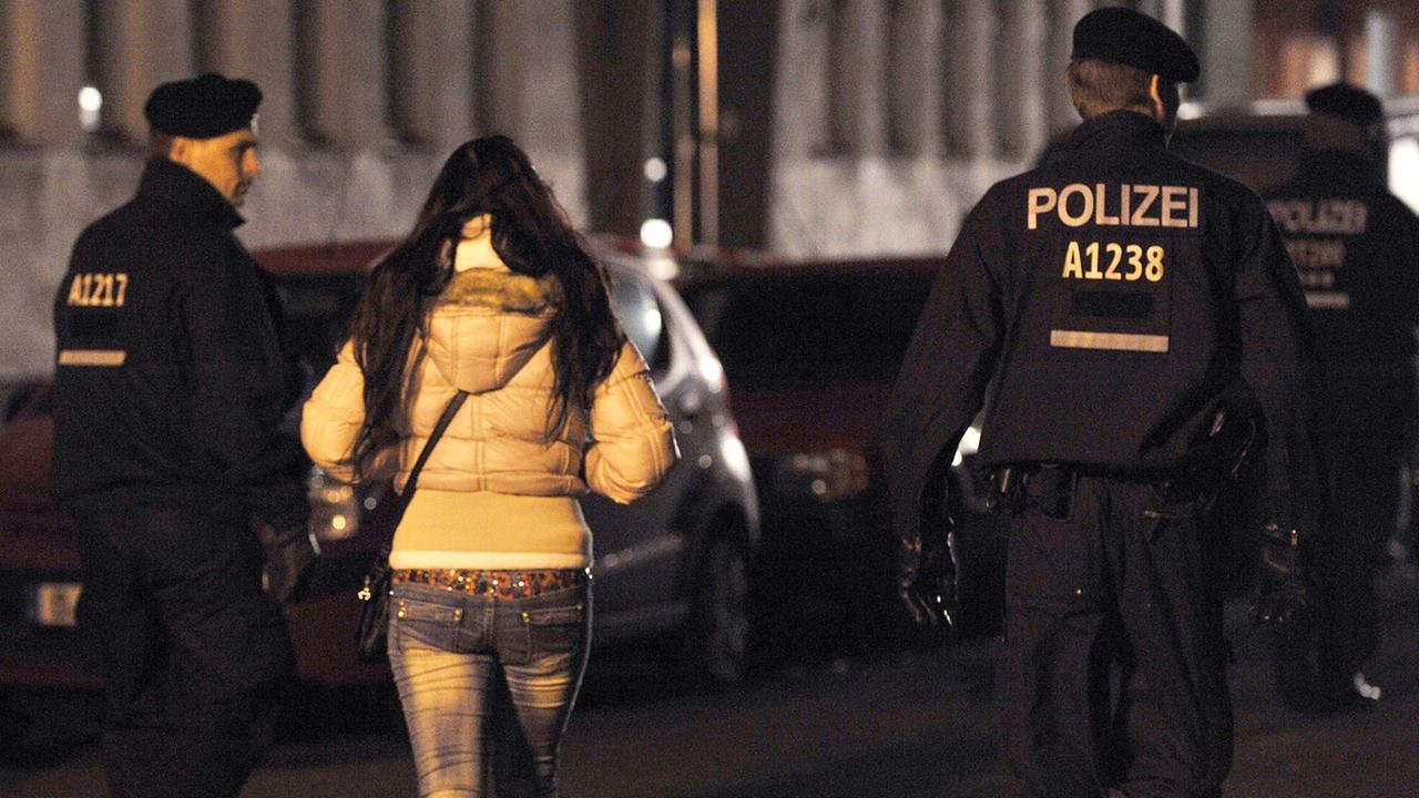 Polizisten begleiten bei einem Polizeieinsatz mit Durchsuchungen am 08.11.2013 in der Kurfürstenstraße in Berlin eine Frau zu einem Kontrollpunkt.