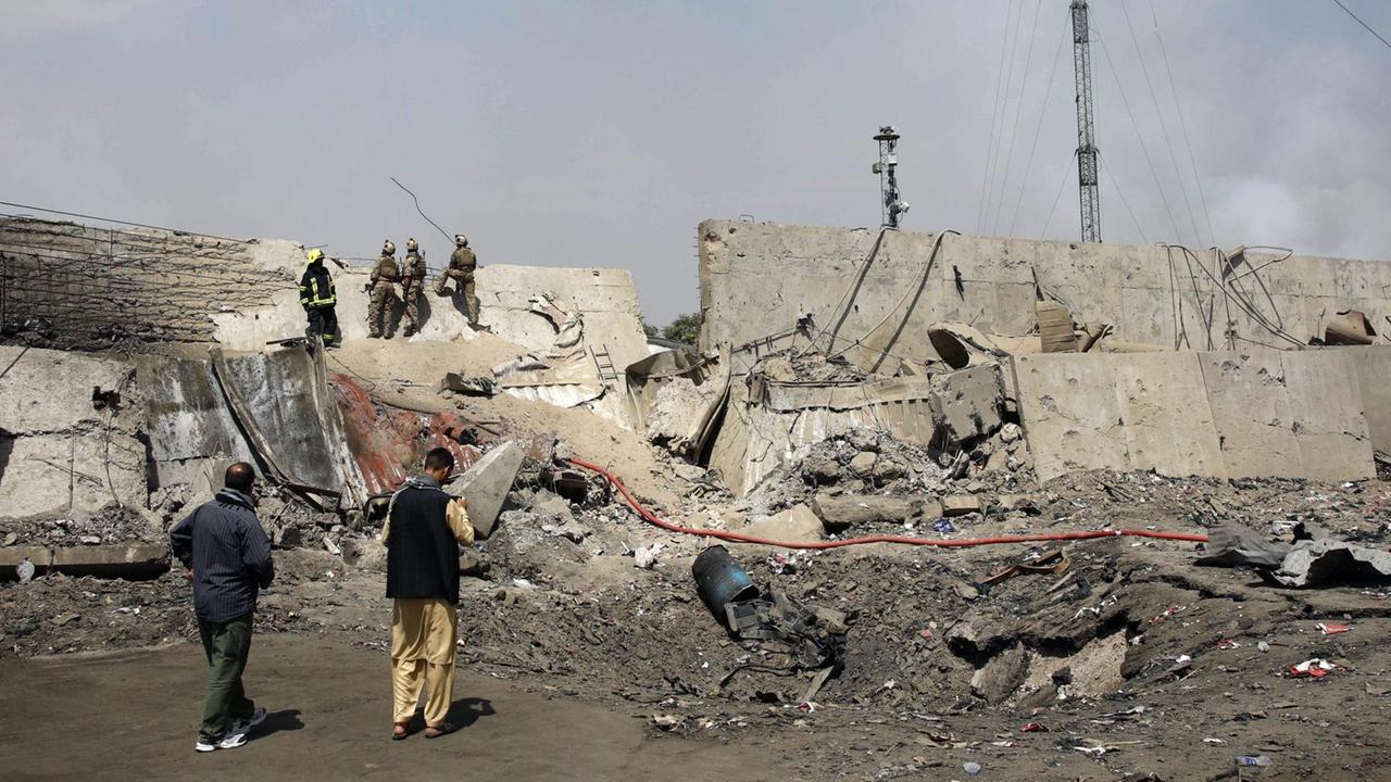Afghanische Sicherheitsleute  stehen am Rand des Kraters einer Explosion