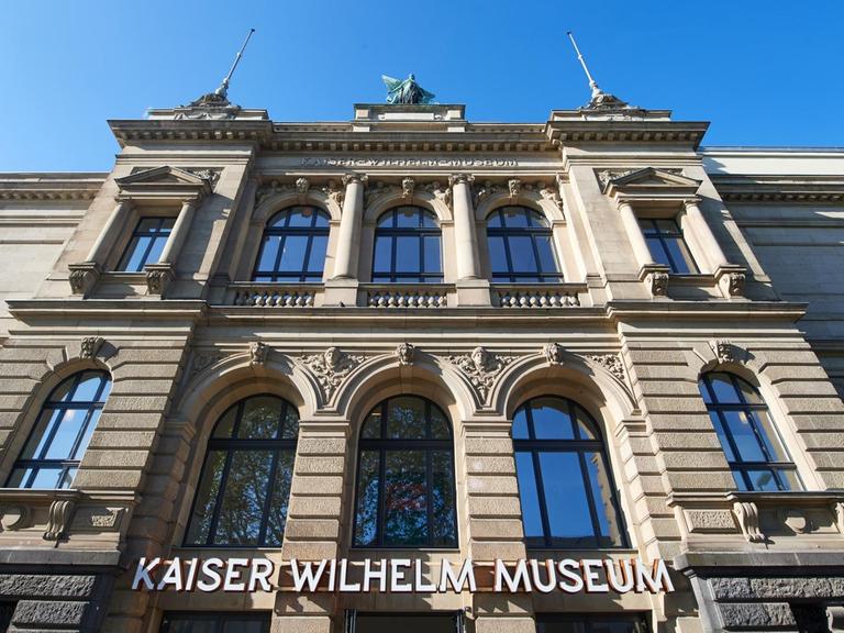 Die Fassade des Kaiser-Wilhelm-Museums in Krefeld mit Namenszug über dem Eingang aus der Froschperspektive.