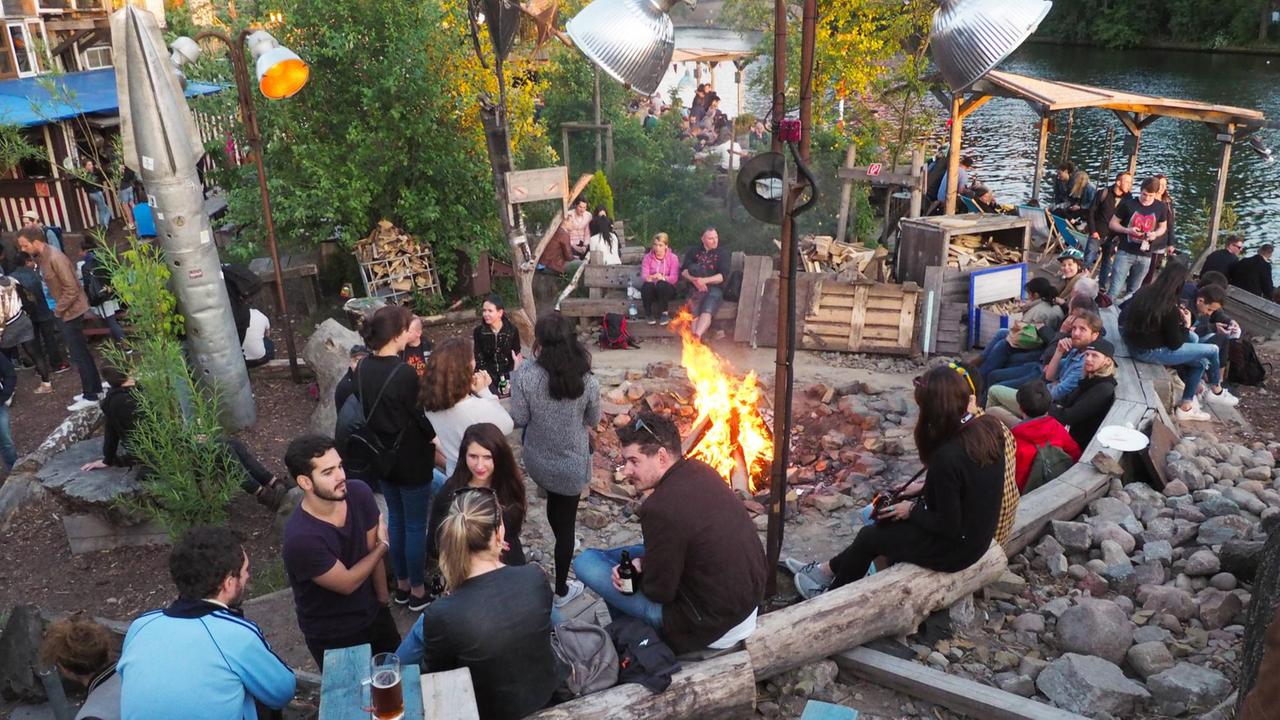 Besucher am Lagerfeuer im Holzmarkt am Ufer der Spree 