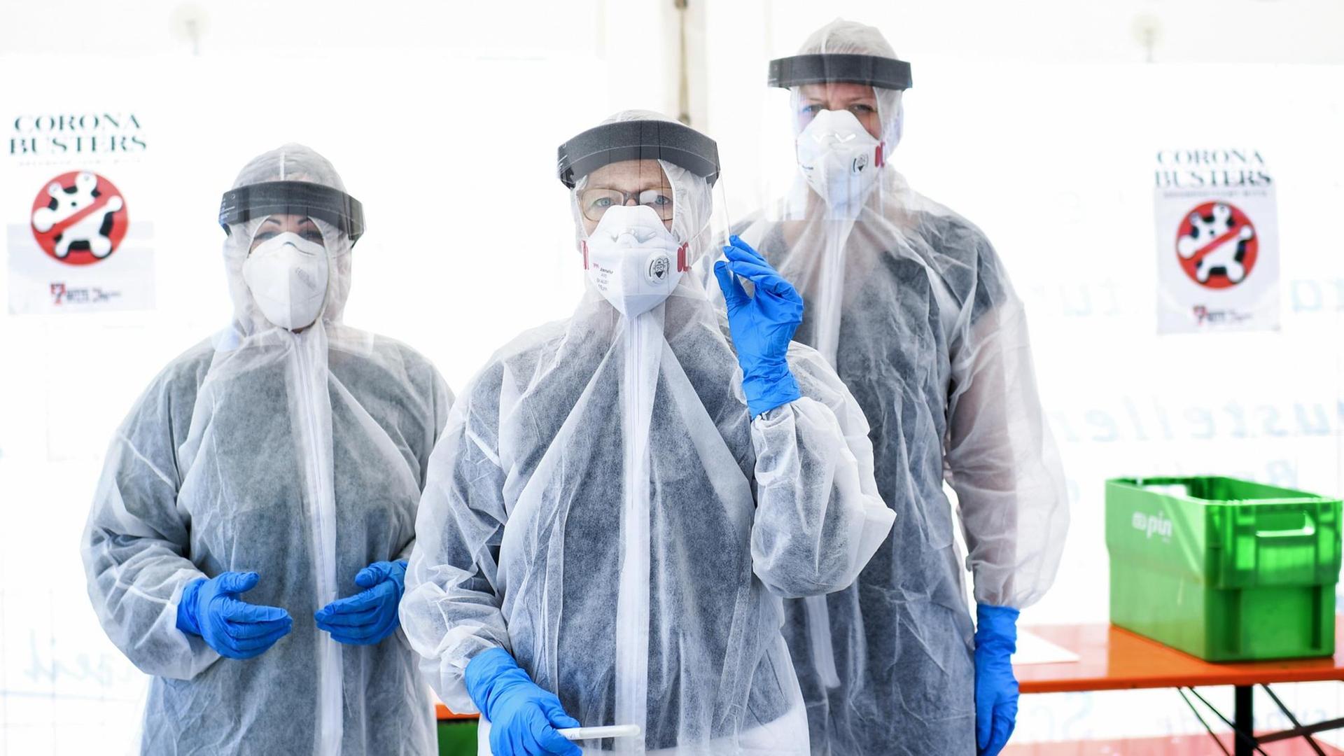 Drei Mitarbeiter vom Gesundheitsamt in Berlin Mitte stehen in Schutzkleidung, in der ambulanten Corona-Test- Einrichtung.